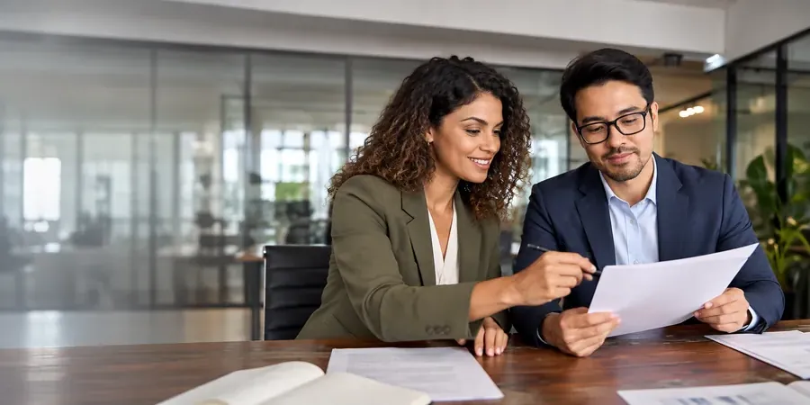 A client and a financial adviser looking over documents at a meeting table