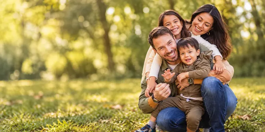 A young family laughing together on the grass in a park