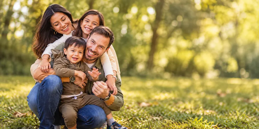 A young family laughing together on the grass in a park