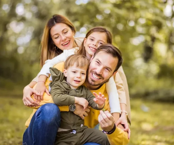 Parents crouching in a park with their two young children, all laughing