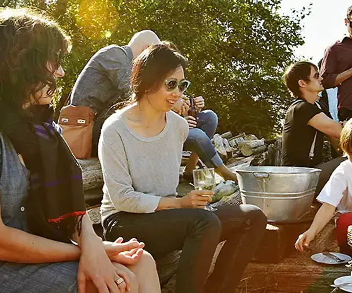 Friends of several ages sitting together on the grass at a picnic